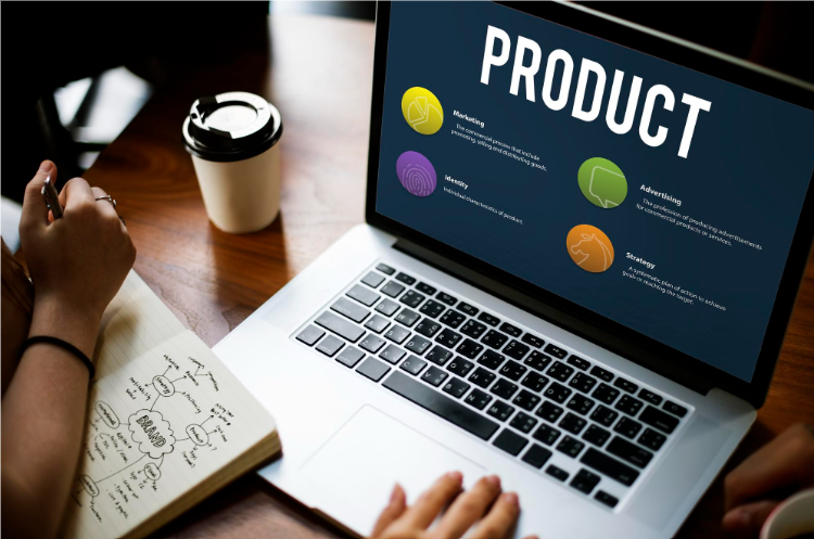 Person working on a laptop displaying a product strategy presentation with marketing, advertising, identity, and strategy elements, alongside a notebook and coffee cup on a desk.